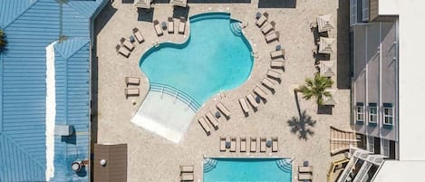 An aerial view of a resort with a swimming pool, sun loungers, and a sign for Tybee Vacation Rentals.