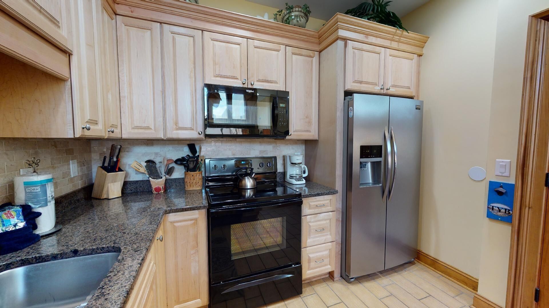 Una cocina con armarios de madera, un refrigerador de acero inoxidable, un microondas y una estufa.