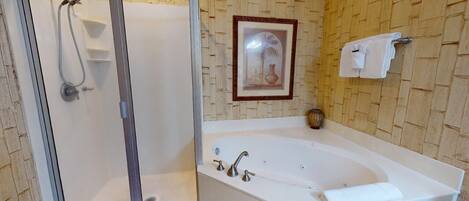 A bathroom with a glass-enclosed shower, a freestanding bathtub, and a framed picture on the wall.