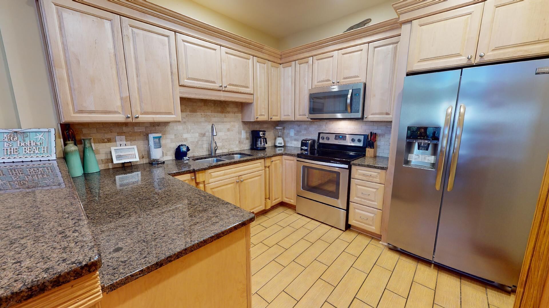 A kitchen with granite countertops, wooden cabinets, a stainless steel refrigerator, a microwave, and an oven.