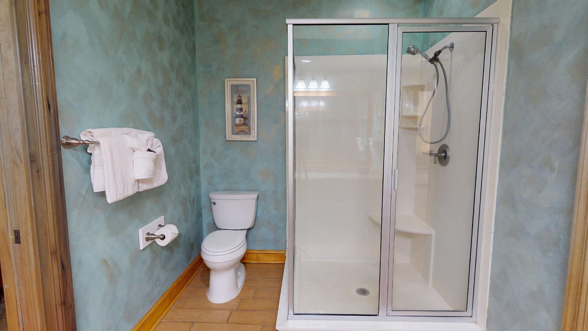 Ein Badezimmer mit einer gläsernen Duschkabine, Toilette und einem Handtuchhalter mit Handtüchern.