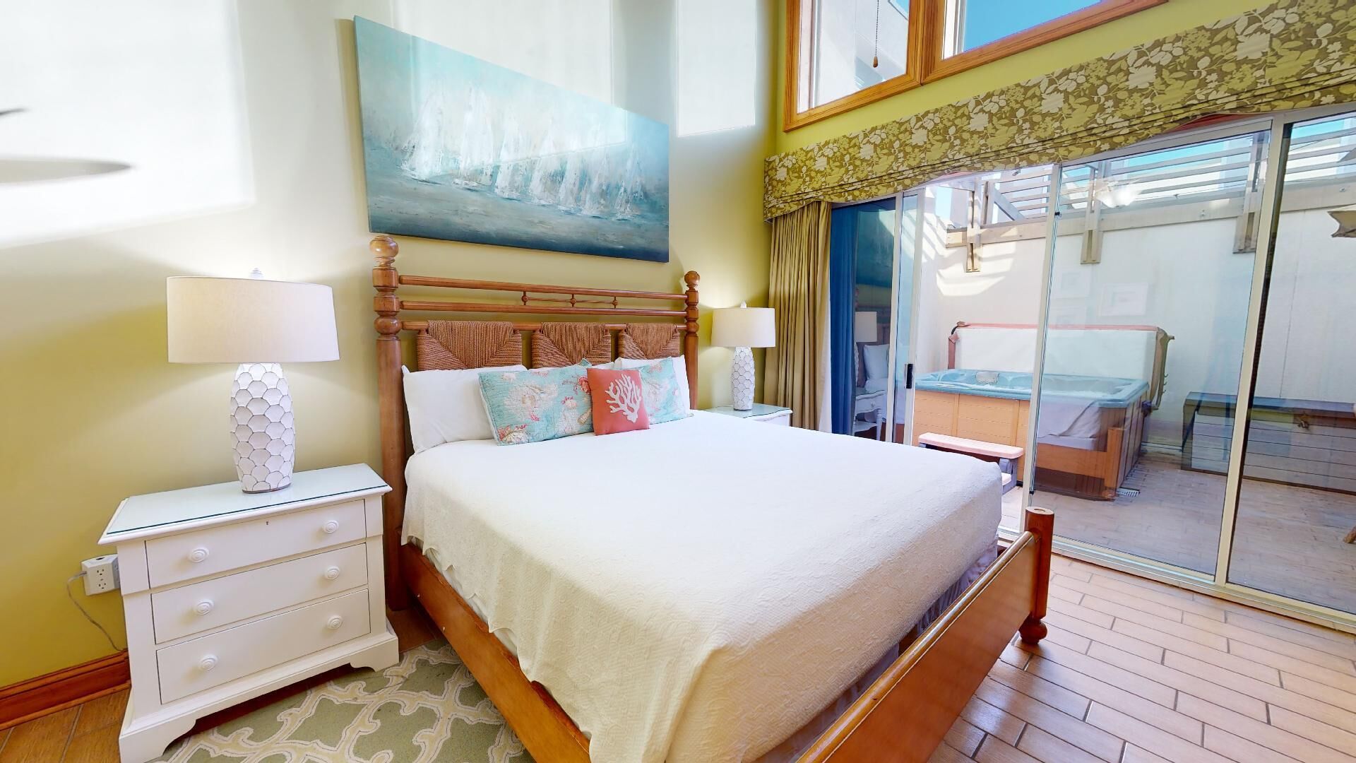 A hotel room with a bed, nightstands, a painting, and a sliding glass door leading to a balcony.