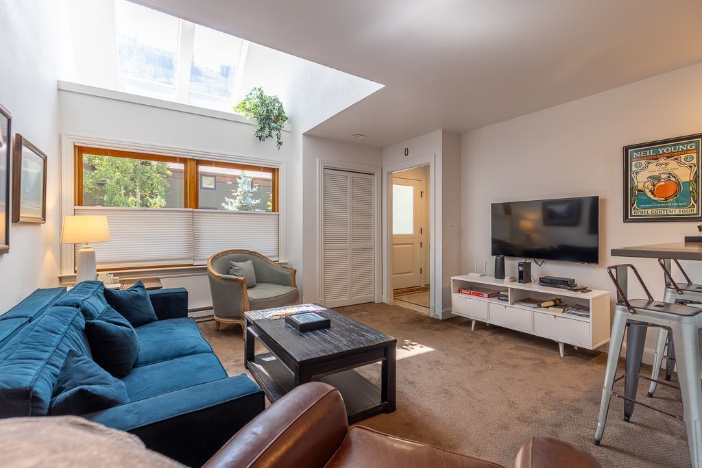 Ett modernt vardagsrum med en soffa, ett soffbord, en tv och en bokhylla.