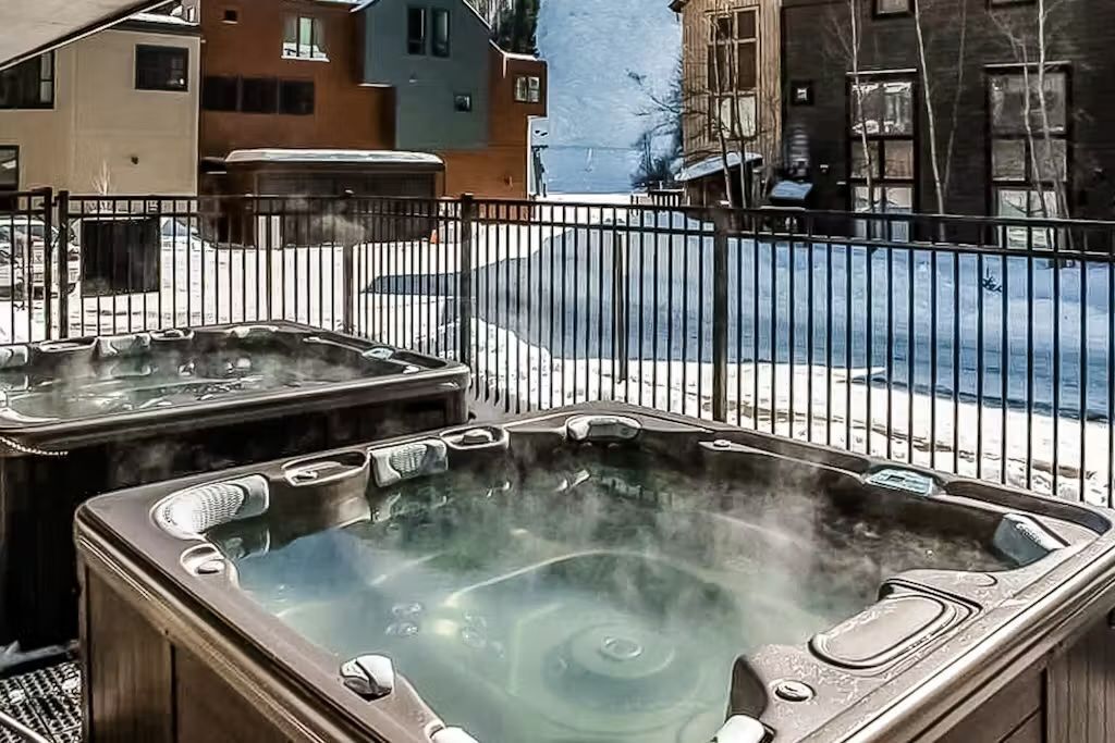 A hot tub area with a metal fence and buildings in the background.