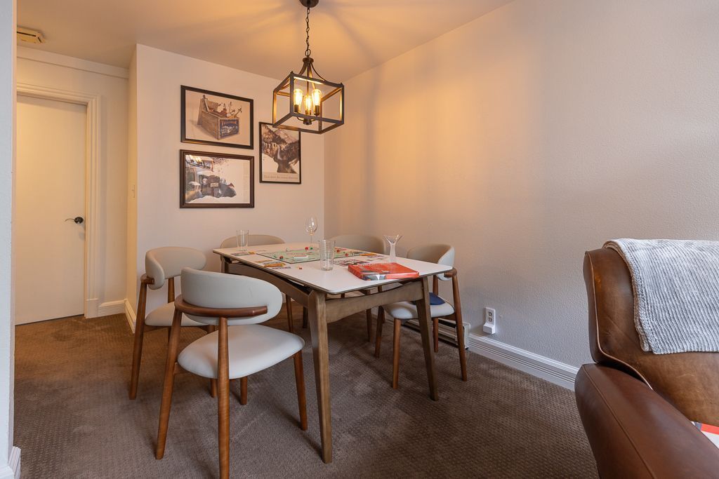 A dining area with a table, chairs, and a hanging light fixture.