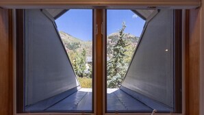 Quarto com uma grande janela e vista para uma paisagem montanhosa.