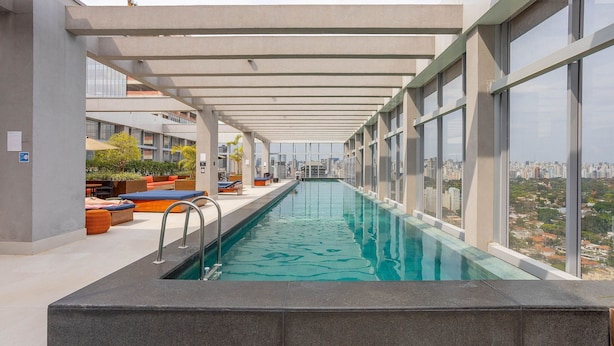 A rooftop swimming pool with a city view, lounge area with seating, and a covered walkway. - Apt w/ Balcony & View, 280m From the Metro Hbw2317 (São Paulo)