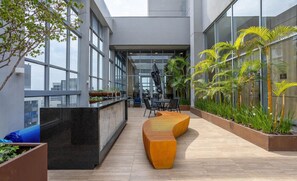 A modern indoor space with large windows, a curved seating area, and potted plants. - Apt w/ Balcony & View, 280m From the Metro Hbw2317 (São Paulo)