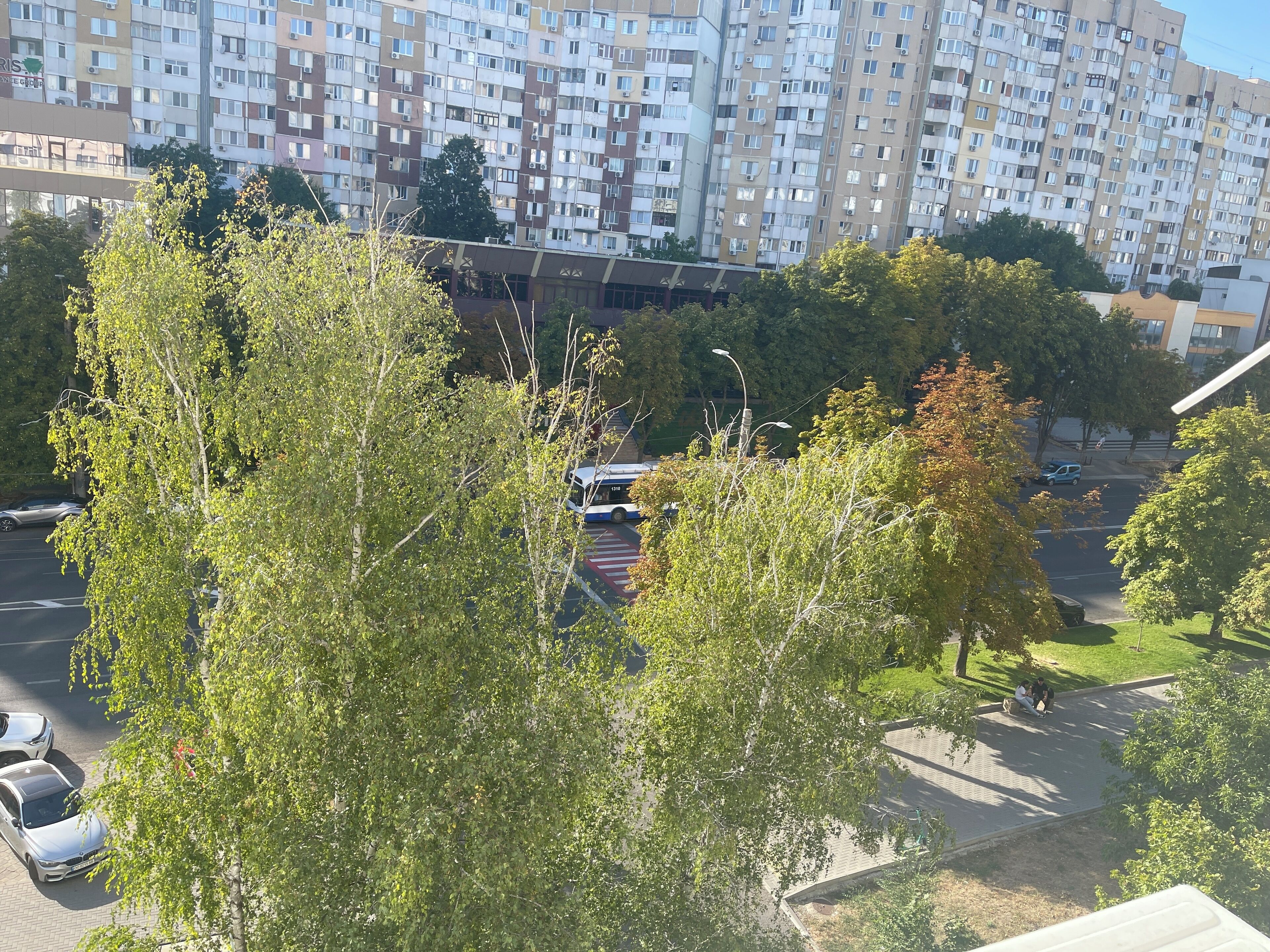 A residential area with apartment buildings, trees, and parked cars.