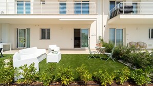 En toetagers bygning med balkon, lille patio med udendørs møbler og en velplejet græsplæne.