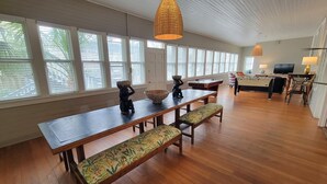 A spacious room with a long wooden table, benches, and a pool table. - The Wheel House by Tybee Vacation Rentals (Tybee Island)