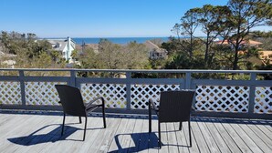 A wooden deck with two wicker chairs facing a white lattice railing. - The Wheel House by Tybee Vacation Rentals (Tybee Island)