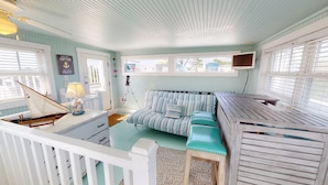 A nautical-themed room with a striped sofa, a small table, and a sailboat model.