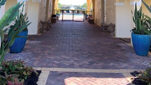 An arched entrance with a brick pathway leading to a pool area, decorated with evergreen garlands and red bows.