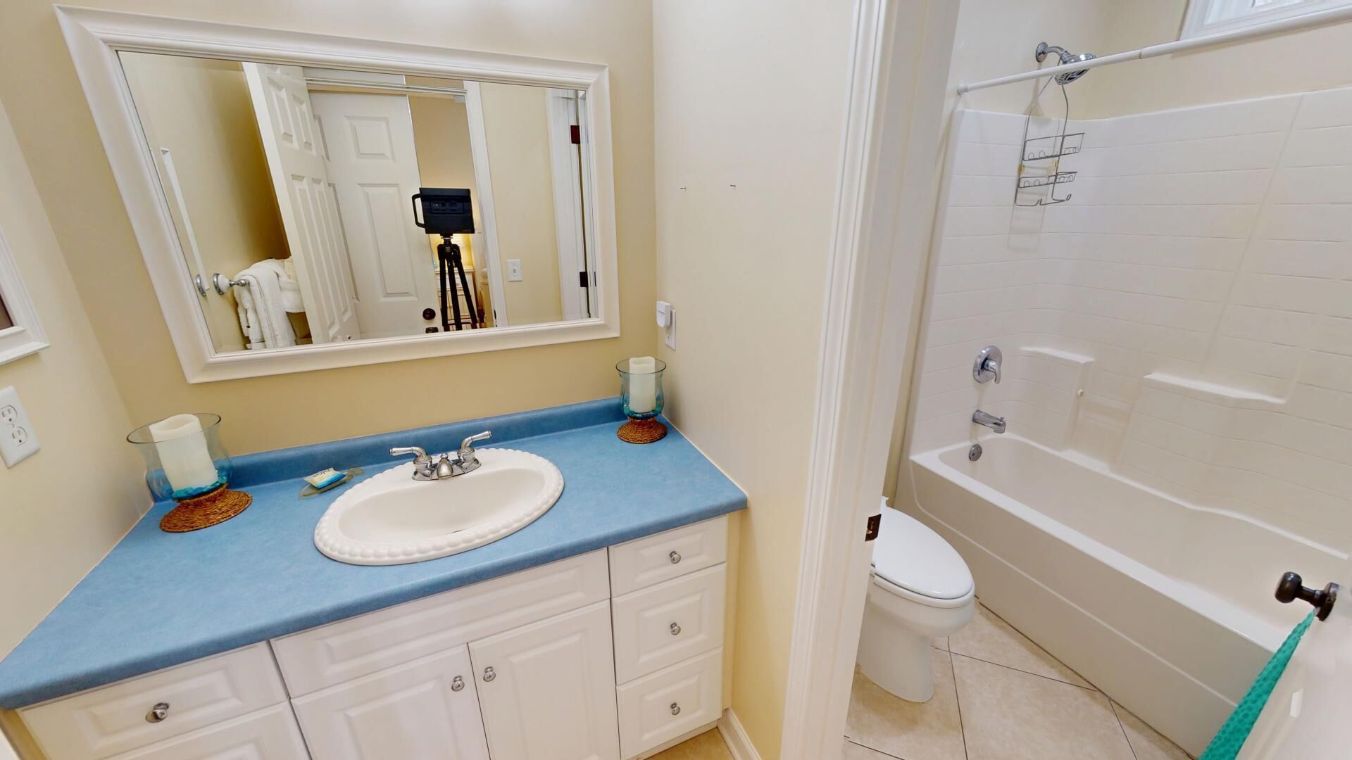 Un baño con lavamanos blanco, encimera azul y bañera.