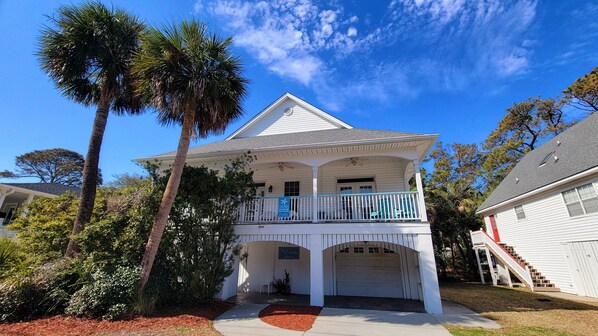A two-story white house with a balcony, a garage, and a pool area.