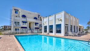 A hotel with a swimming pool, outdoor seating, and a clear blue sky. - Heated pool, hot tub, and private beach access! (Cape Canaveral)