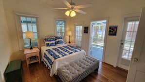 A bedroom with a bed, two bedside tables, a ceiling fan, and a window.