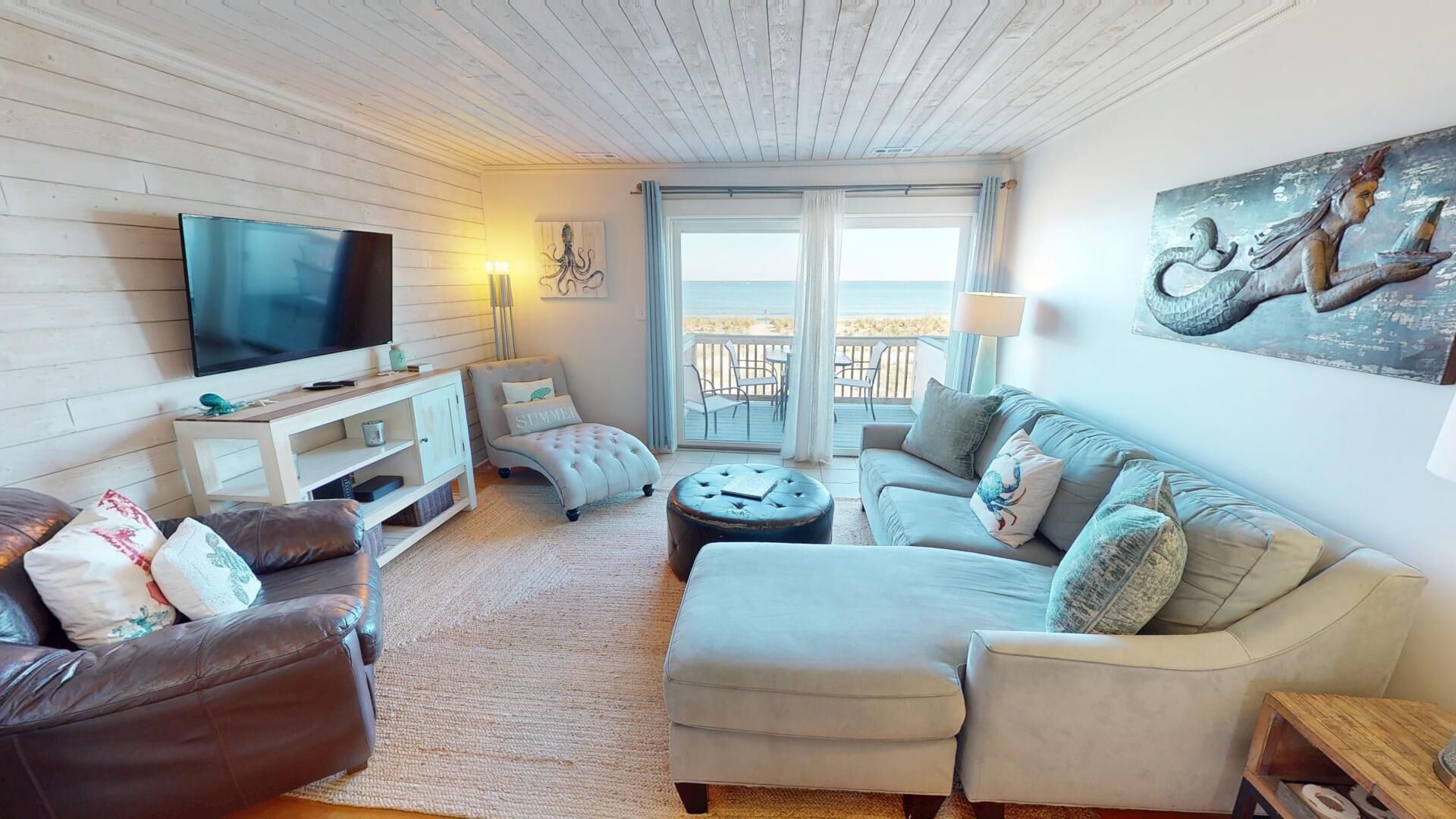 En hyggelig stue med et fladskærms-TV, behagelige siddepladser og en balkon med udsigt.
