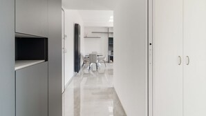 Un pasillo moderno con comedor, paredes blancas y una puerta a la derecha.