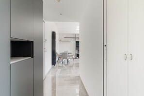 Un pasillo moderno con comedor, paredes blancas y una puerta a la derecha.