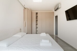 Un dormitorio minimalista con cama, armario y televisor.