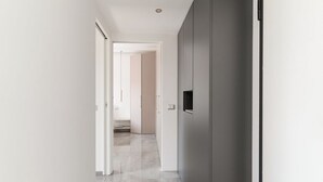 Un couloir avec une porte donnant sur une pièce, un interrupteur et un luminaire fixé au mur.
