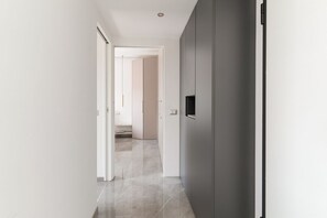 A hallway with a door leading to a room, a light switch, and a wall-mounted light fixture.