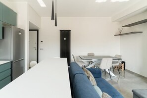 Una cocina moderna con refrigerador integrado, un comedor con mesa y sillas, y un sofá azul.