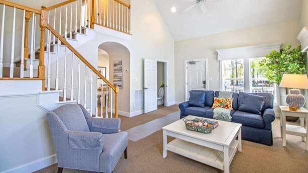 A spacious living room with a staircase, a blue sofa set, and a coffee table.