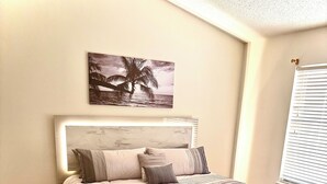 A bedroom with a bed, a marble-patterned rug, a headboard, and a wall-mounted picture.