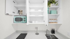 Een moderne keuken met witte kasten, een ingebouwde magnetron, een spoelbak en een aanrecht.