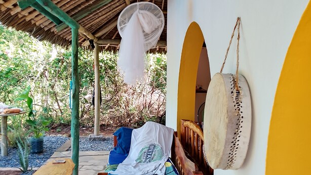 A wooden bed with a blue and green striped pillow, a white cloth, and a wooden headboard.