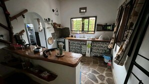 A kitchen with a stone floor, a wooden counter, a stove, and a window with a view of greenery.