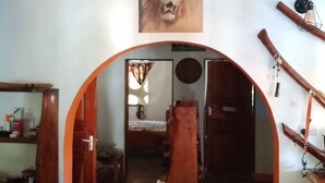 A room with a lion painting, a wooden archway, a stone floor, and a bed with a striped blanket.