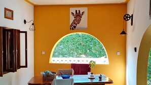 A dining area with a table, chairs, and a window with a giraffe poster.