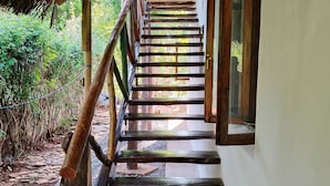 A wooden staircase leading to a covered area with a view of greenery outside.