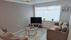 A modern living room with a flat-screen TV, two sofas, a coffee table, and a patterned rug. - The Croft House Near Birmingham Airport and Nec (Birmingham)