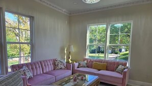 Un salon spacieux avec deux canapés roses, une table basse en verre et une lampe.