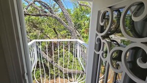 Un balcon doté d’une balustrade blanche, offrant une vue sur les arbres et le ciel.