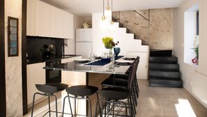 Une cuisine moderne dotée d’un îlot central, de tabourets de bar et d’un escalier menant à une mezzanine.
