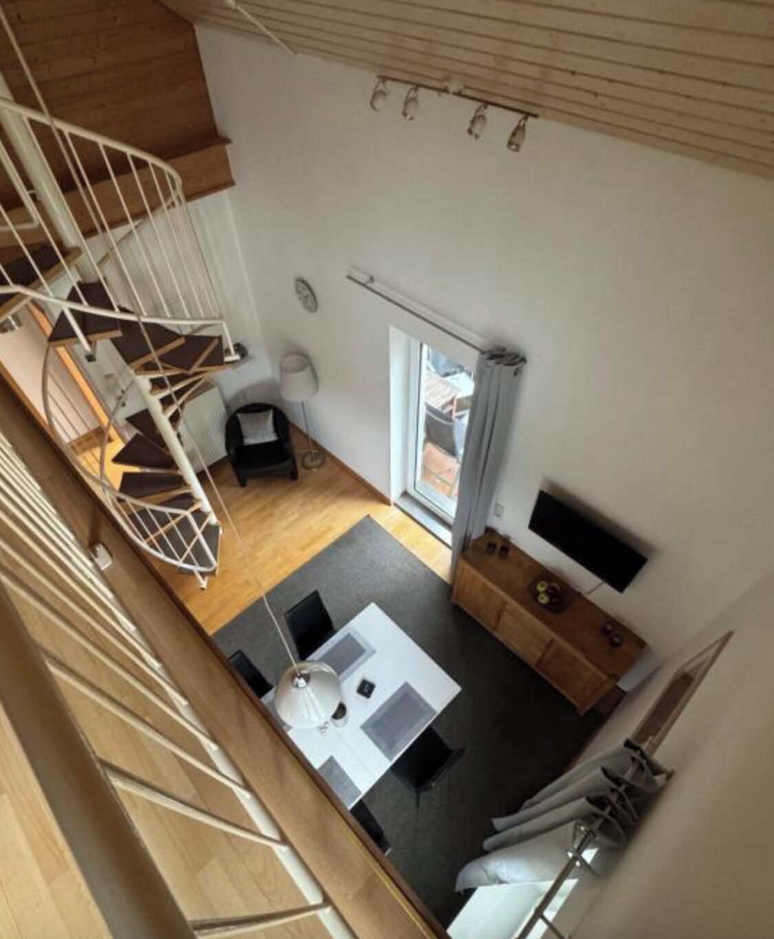 A modern interior with a spiral staircase, a dining area, and a large window.