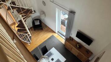 A modern interior with a spiral staircase, a dining area, and a large window.