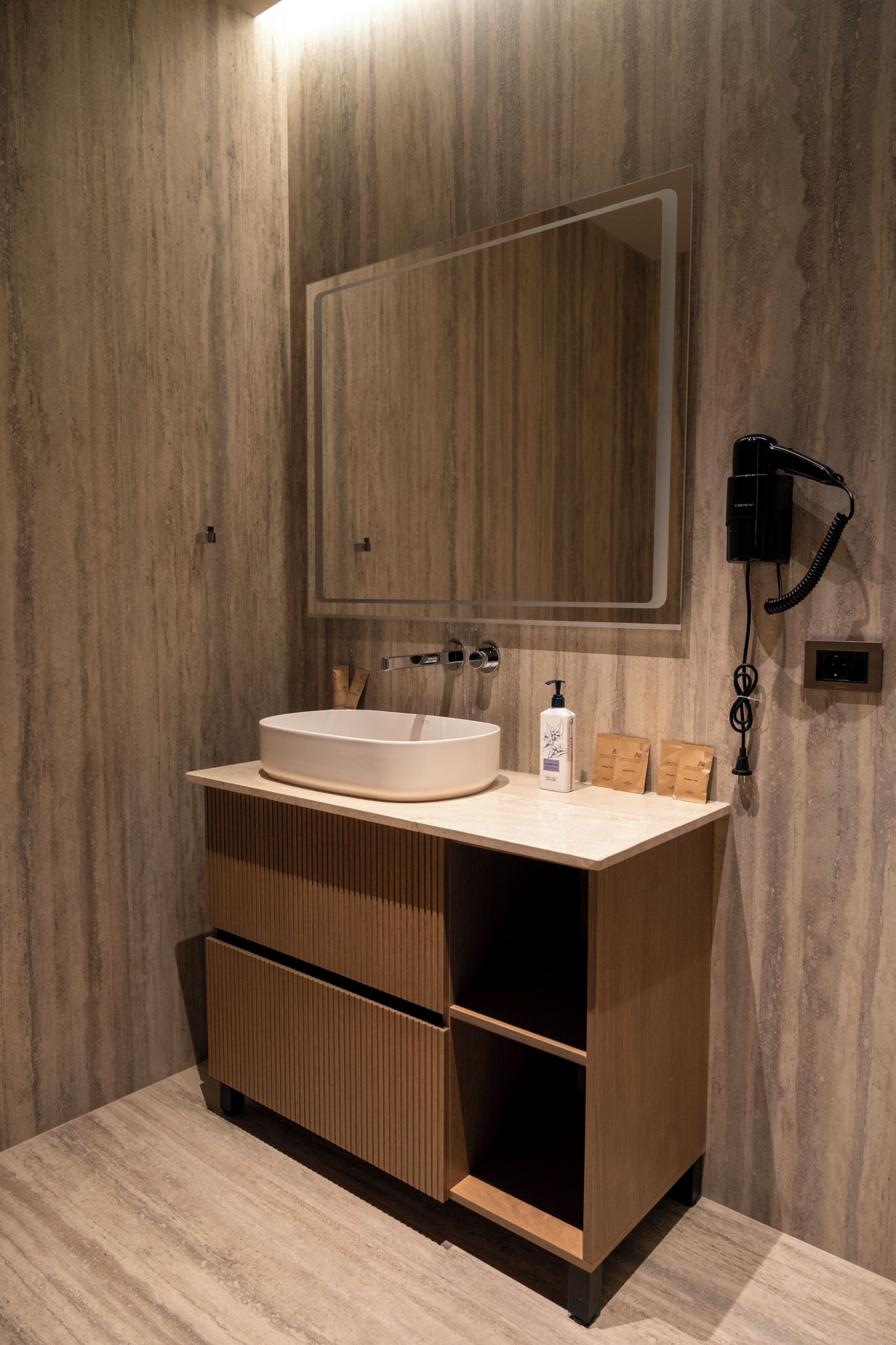 A modern bathroom with a large mirror, a sink, and a hairdryer mounted on the wall.