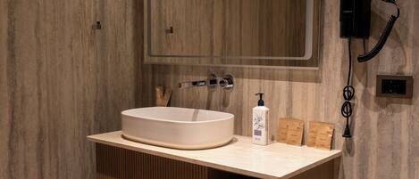 A modern bathroom with a large mirror, a sink, and a hairdryer mounted on the wall.