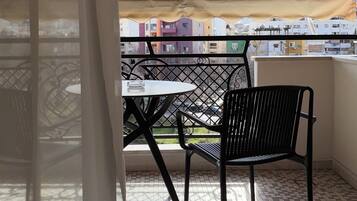 Ein Balkon mit Tisch und Stühlen, Blick auf Gebäude und ein Fliesenboden.