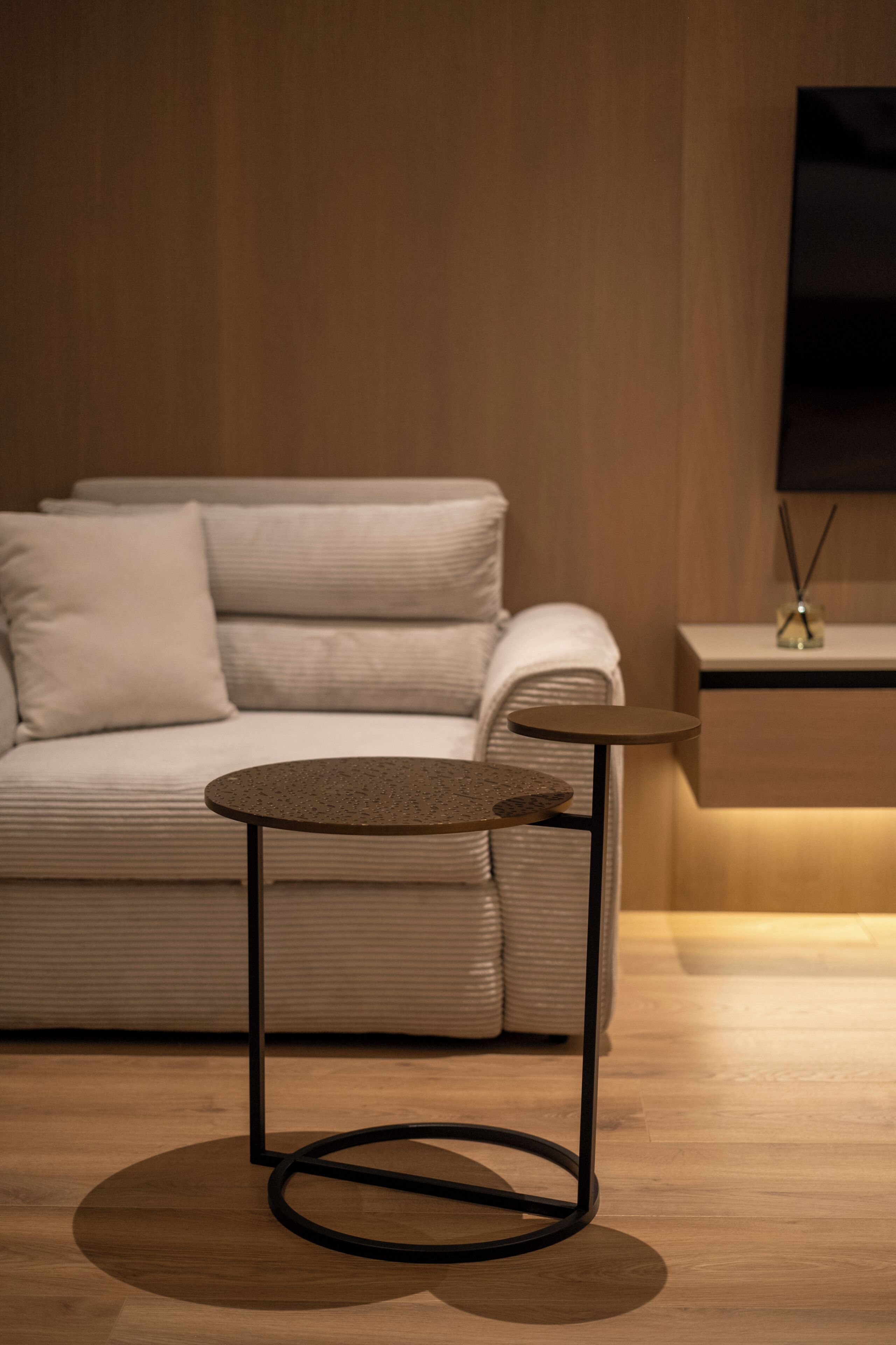 A modern room with a sofa, a small round table, and a wall-mounted TV.