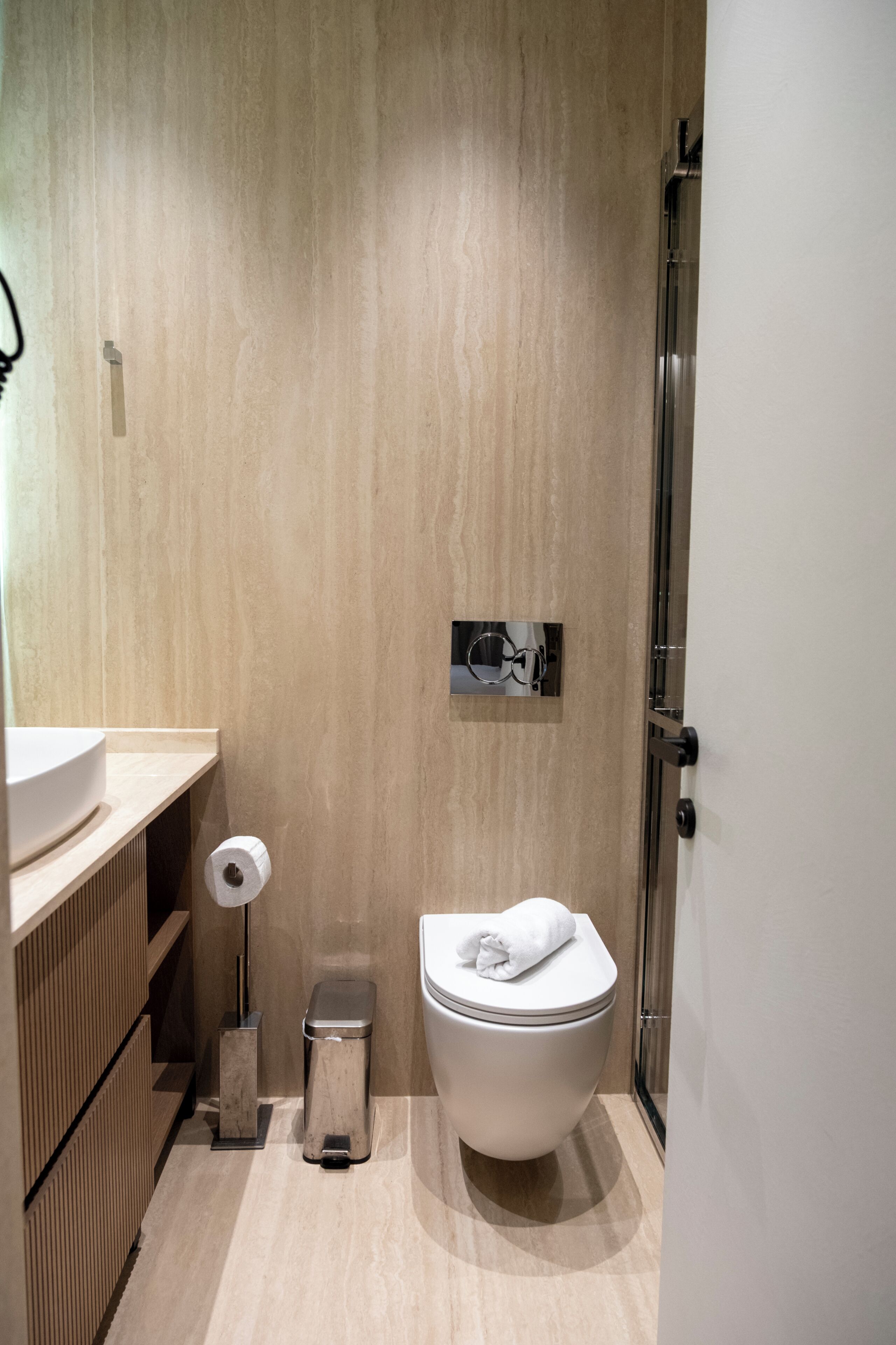 Un baño moderno con inodoro, lavamanos y un cubo de basura.