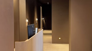 A hallway with a reception desk, carpeted floor, and recessed lighting.