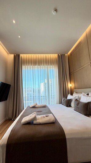 Hotelkamer met een groot bed, een flatscreen televisie, uitzicht over de stad en een plafondlamp.